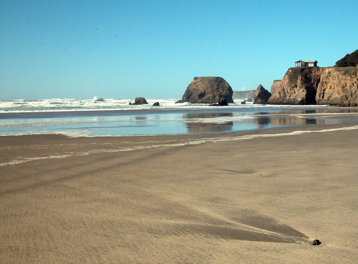 Wet sand and low surf below a headland on a clear morning