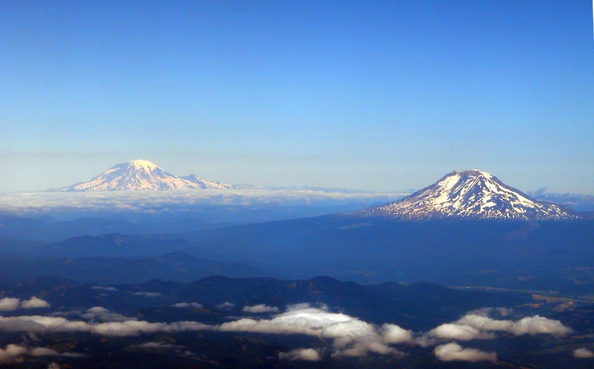 Two snow-capped Oregon volcanoes standing above the cloud layer, seen from the air